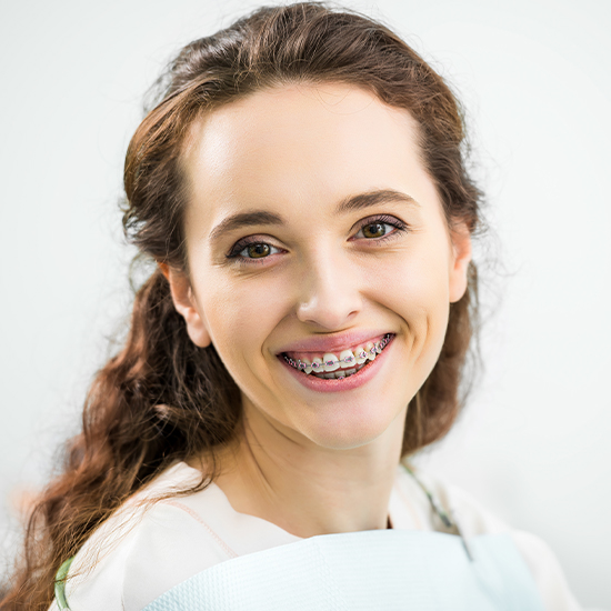 Woman with adult orthodontics pointing to her smile