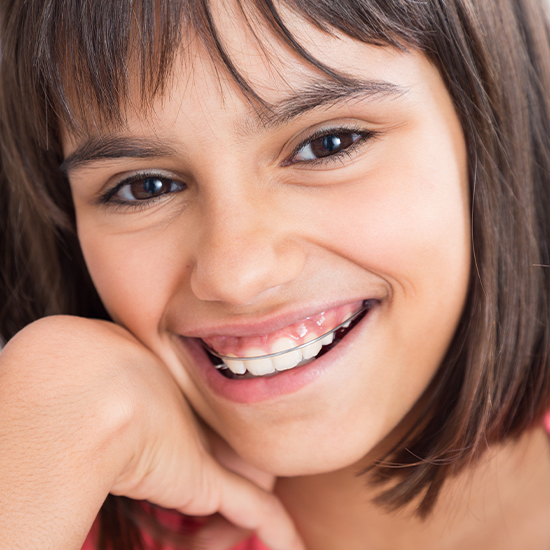 Smiling girl wearing an orthodontic appliance