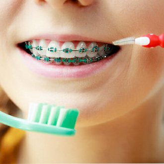a patient with braces brushing their teeth