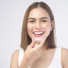 Woman smiling while holding Invisalign in Rutland