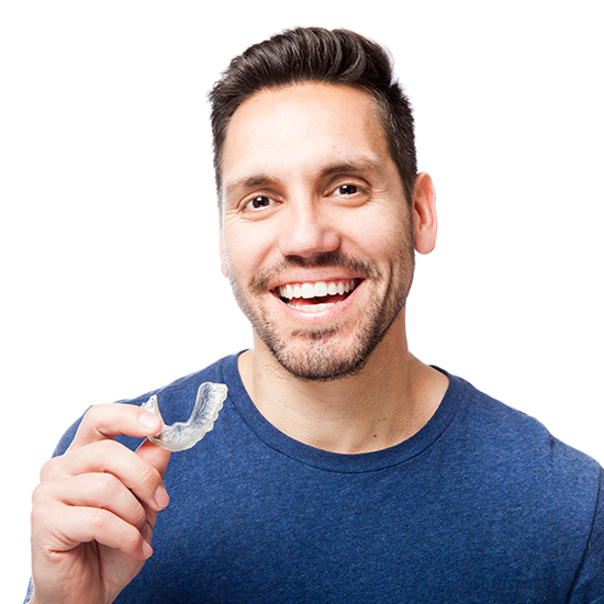 Smiling man holding Invisalign alignment tray