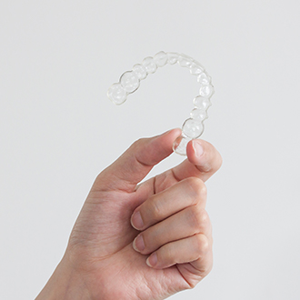 Hand holding an Invisalign tray