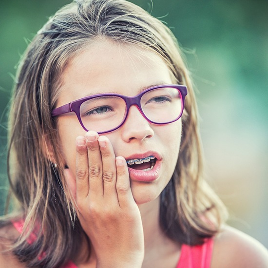 Closeup of girl experiencing toothache with braces