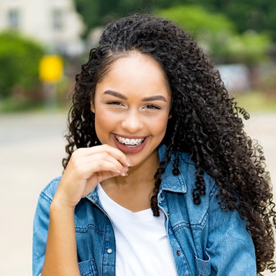 A young female pointing to her braces after seeing an orthodontist in Worcester