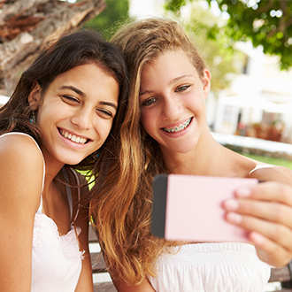 Two teen girls taking a picture together one with braces